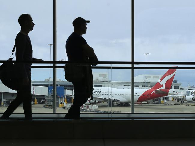 SYDNEY, AUSTRALIA - MARCH 10: Two passengers walk past a Qantas jet at the International terminal at Sydney Airport on March 10, 2020 in Sydney, Australia. Qantas has cut almost a quarter of its international capacity for the next six months as travel demands fall due to fears over COVID-19. The airline today announced it was altering routes to London and would be parking eight of their 12 A380 aircraft. (Photo by Mark Evans/Getty Images)