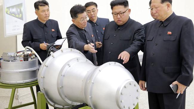 North Korean leader Kim Jong-un (C) looking at a metal casing with two bulges at an undisclosed location.