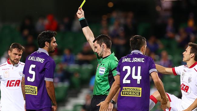 Referee Jarred Gillett shows Rhys Williams of the Glory a yellow card.
