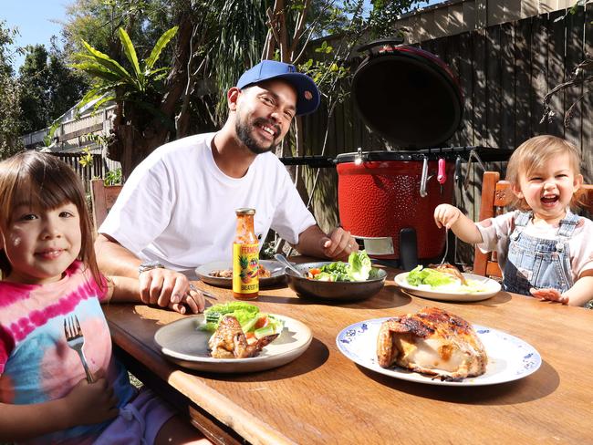 Chef Louis Tikaram enjoying BBQ peri peri chicken with his daughters Maelle, 4, and Colette, 2, in their backyard at Norman Park, Brisbane. Picture: Liam Kidston.