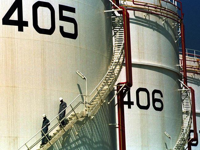 FILE- In this Sept. 25, 2000 file photo, two workers climb down from one of the tanks in an oil tank-farm in Jebel Ali, 25 miles (40 km) south of Dubai in the United Arab Emirates. The historic crash in oil prices in the wake of the novel coronavirus pandemic is reverberating across the Middle East as crude-dependent countries scramble to offset losses from a key source of state revenue. The economies of all the Arab Gulf oil exporters are expected to contract this year. (AP Photo/Kamran Jebreili, File)