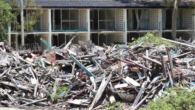 A massive rubbish pile sits on the old tennis courts of Great Keppel Island resort, with the trashed L-shaped accommodation block in the background.