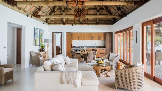 Villas at Kokomo Private Island Fiji feature crisp white upholstered furniture and thatched roofs.