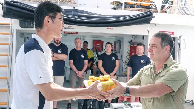 Marine Archaeologist David Steinberg presents Takenobu Hamaguchi with sand from the vicinity of the Japanese WWII wreck of I-124 submarine as a dive expedition returns from a Heritage documentation trip. Picture: Glenn Campbell