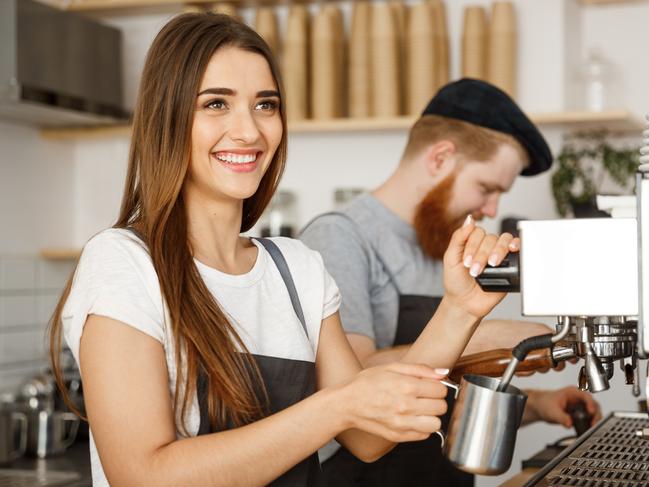 Coffee Business Concept - portrait of lady barista in apron preparing and steaming milk for coffee order with her partner while standing at cafe. Picture: iStock.