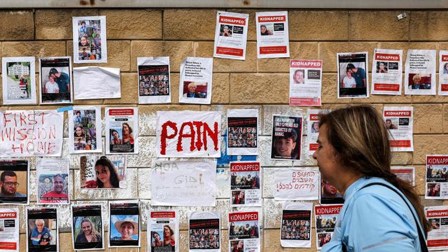 A woman looks at posters showing hostages. Picture: AFP