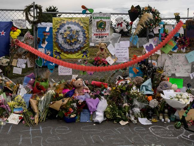 A boy looks at flowers and tributes displayed in memory of the twin mosque massacre victims along the road outside the Linwood mosque (back C) in Christchurch on March 25, 2019. - The slaughter of 50 people at Friday prayers in two Christchurch mosques on March 15 shocked the normally laid-back country and prompted global horror, heightened by the gunman's cold-blooded livestreaming of the massacre. (Photo by ANTHONY WALLACE / AFP)