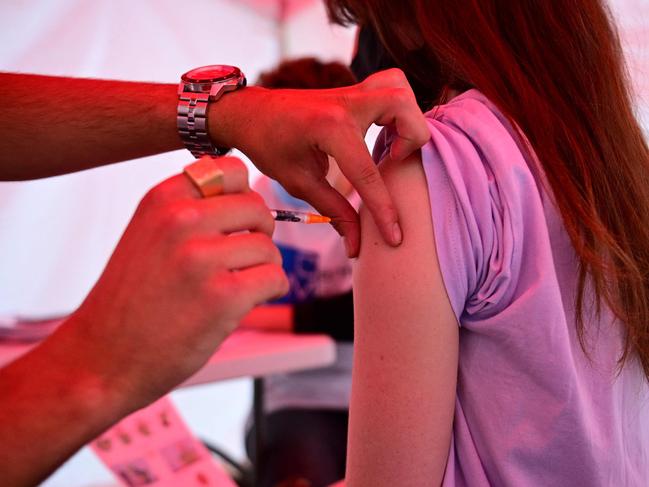 A youth receives a dose of Comirnaty vaccine by Pfizer-BioNTech against Covid-19 on June 29, 2021 at an outdoor vaccination centre set up by the French Red Cross at Republique square in Paris. - Functionning without appointments, the centre gives the priority to delivery drivers. (Photo by MARTIN BUREAU / AFP)