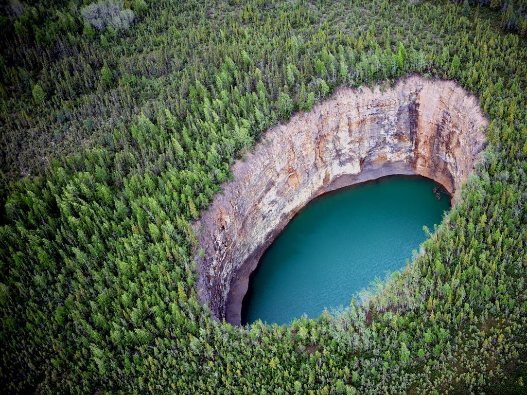 <span>4/20</span><h2>Bear Rock Sinkhole, Northwest Territories</h2><p> Deep in the wilds, dozens of sinkholes pit the dense forest, appearing like vibrant cerulean pools amid a blanket of green. The most photogenic of these is the bewildering <a href="https://spectacularnwt.com/" target="_blank">Bear Rock Sinkhole</a>, formed by the collapse of a vast cave under the earth’s surface, between the towns of Tulita and Norman Wells.</p>