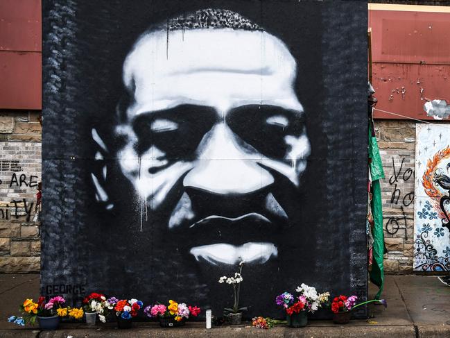TOPSHOT - A woman walks near the makeshift memorial of George Floyd before the third day of jury selection begins in the trial of former Minneapolis Police officer Derek Chauvin who is accused of killing Floyd, in Minneapolis, Minnesota on March 10, 2021. - The first jurors were selected on March 9, 2021 in the high-profile trial of the white police officer accused of killing George Floyd, an African-American man whose death laid bare racial wounds in the United States and sparked 