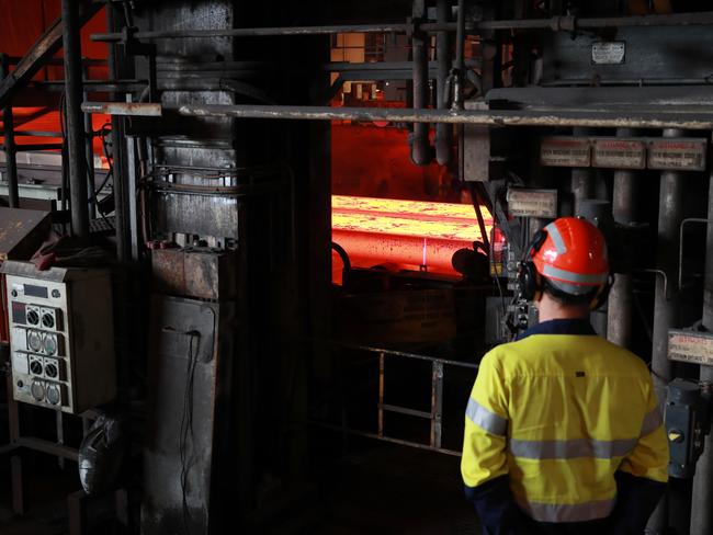 BUDGET2022: A worker watches as slabs of molten metal are cut to length at the Slabcaster at BlueScope Steel manufacturing plant in Port Kembla. John Feder