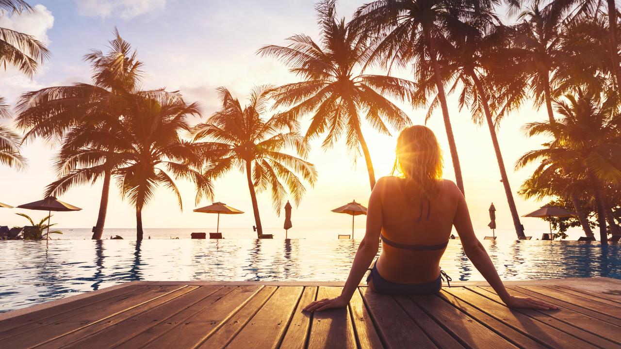 ESCAPE: TIGHT TRAVEL, Angus Kidman - 3MAR19-  Woman enjoying vacation holidays at luxurious beachfront hotel resort with swimming pool and tropical lansdcape near the beach Picture: iStock