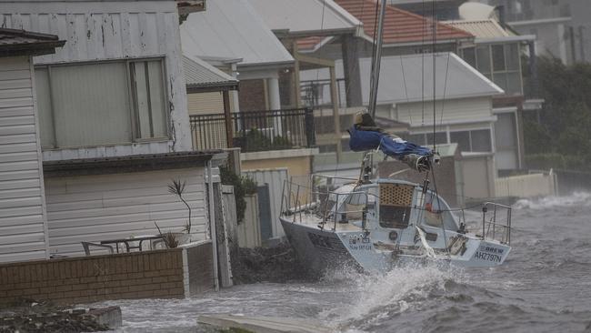 A boat smashes against a house at Belmont near the Belmont Sixteens Sailing club on Ross St Belmont. Picture: Owen hammond.