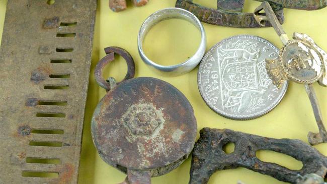 Mark Spencer of CQ Detectorists shows a florin ring, lead cat, war medals, Victorian skirt lifter, miners heel clip, harmonica part and child's toy. Picture: Jann Houley