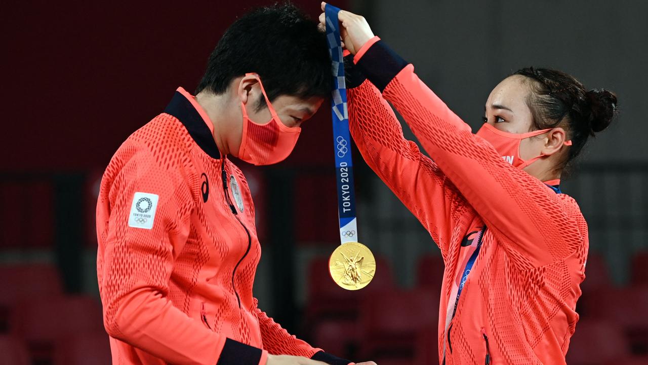 Japan's Jun Mizutani receives his gold medal from teammate Japan's Mima Ito on the podium during the mixed doubles table tennis medal ceremony. Picture: Jung Yeon-je/AFP