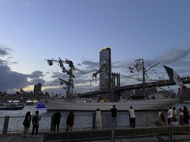 Pedestrians in Brooklyn Bridge Park look as the masted Mexican Navy training ship sits stranded near the Manhattan Bridge after colliding with the Brooklyn Bridge. Picture: Nick Corso via AP