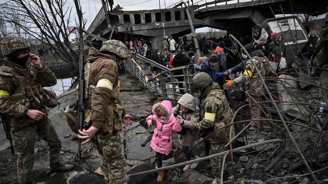 People cross a destroyed bridge as they evacuate the city of Irpin, northwest of Kyiv, during heavy shelling and bombing on March 5, 2022, 10 days after Russia launched a military invasion on Ukraine. Picture: Aris Messinis / AFP