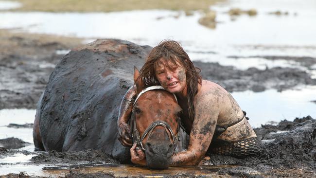 Nicole Graham tries desperately to dig out her horse Astro alongside the CFA and SES. Picture: Peter Ristevski