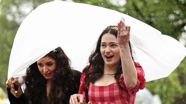 WILD SCENES: Racegoers use a poncho to hide from the rain. (Photo by Martin Keep/Getty Images for VRC)