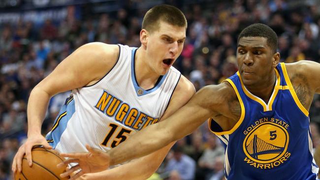 Nikola Jokic #15 of the Denver Nuggets drives to the basket against Kevin Looney #5 of the Golden State Warriors.