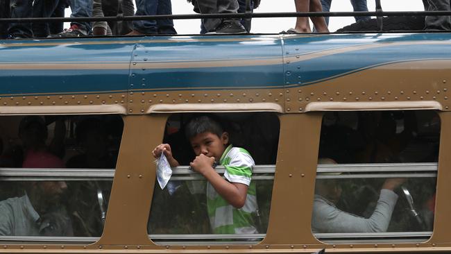 PALIN, GUATEMALA - OCTOBER 18:  Members of a migrant caravan get down from atop a bus to show their IDs at a Guatemalan police checkpoint while en route to the border with Mexico on October 18, 2018 in Palin, Guatemala. The immigrants were part of a migrant caravan of thousands of Central Americans, mostly from Honduras, hoping to eventually reach the United States. U.S. President Donald Trump has threatened to cancel the recent trade deal with Mexico and withhold aid to Central American countries if the caravan isn't stopped before reaching the U.S.  (Photo by John Moore/Getty Images)