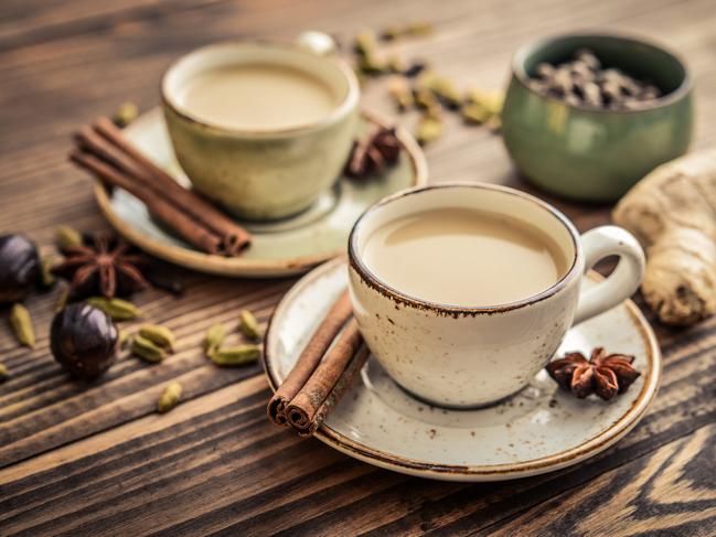 Traditional indian drink - masala chai tea (milk tea) with spices on wooden background