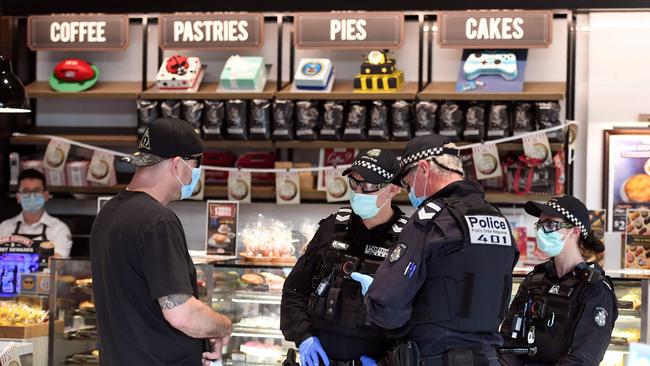 Police question a man after an anti-lockdown protest at a shopping centre in Chadstone, Melbourne. Picture: AFP