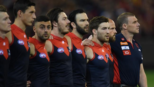 Melbourne coach Simon Goodwin and his players stand for the national anthem.