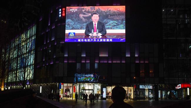 People walk below a giant screen showing news coverage of Xi Jinping's speech to the Asia-Pacific Economic Cooperation (APEC) forum in Malaysia. Picture: AFP.