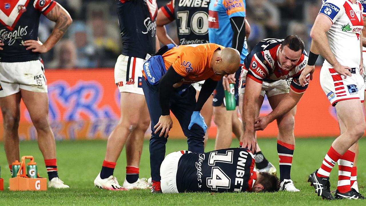Boyd Cordner of the Roosters and a trainer check on the injured Sam Verrills, who tore his ACL at Bankwest Stadium.
