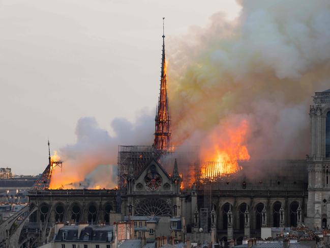 Smoke billows as flames burn through the roof of the Notre-Dame de Paris Cathedral on April 15, 2019, in the French capital Paris. - A huge fire swept through the roof of the famed Notre-Dame Cathedral in central Paris on April 15, 2019, sending flames and huge clouds of grey smoke billowing into the sky. The flames and smoke plumed from the spire and roof of the gothic cathedral, visited by millions of people a year. A spokesman for the cathedral told AFP that the wooden structure supporting the roof was being gutted by the blaze. (Photo by Fabien Barrau / AFP)