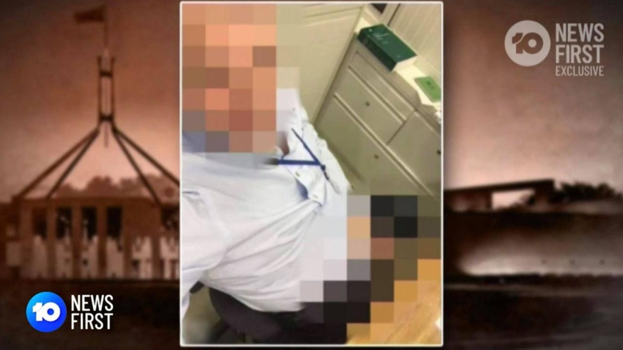 A male staffer sits on a desk and exposes himself, with the Parliament House rule book behind him. Picture: 10 News