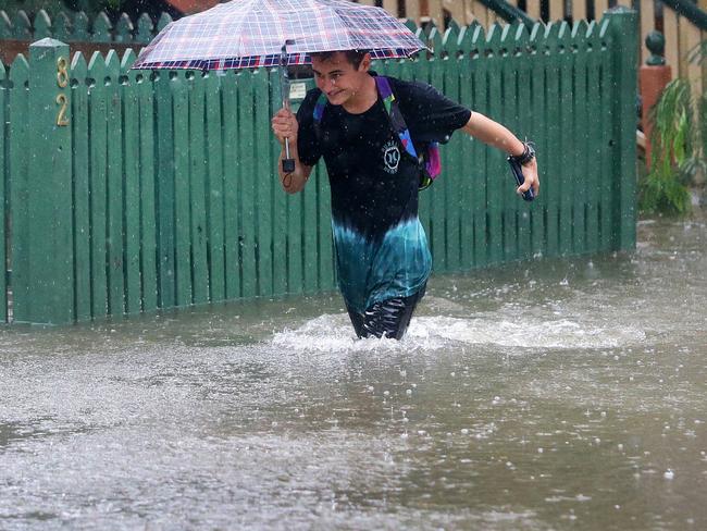 Rigby Wilshire wades through flood waters to get to his home in East Brisbane. Picture: Darren England.