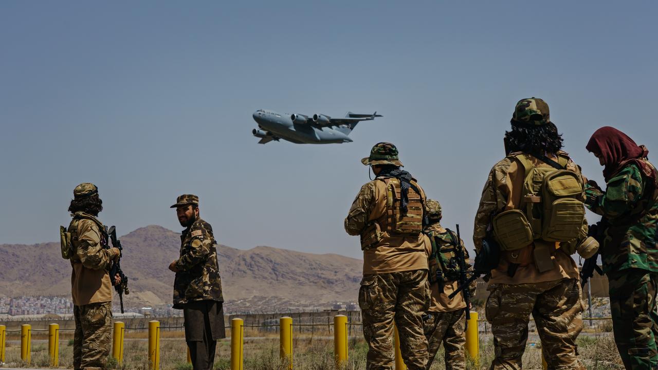 Taliban fighters watch on as an American C-17 Globemaster takes off at the Hamid Karzai International Airport in Kabul, Afghanistan. Picture: Marcus Yam/Los Angeles Times