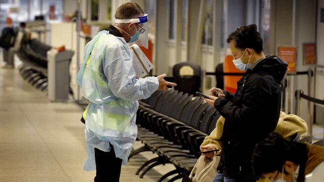 A health official speaks to passengers arriving at Melbourne Airport from Sydney. Picture: Andrew Henshaw