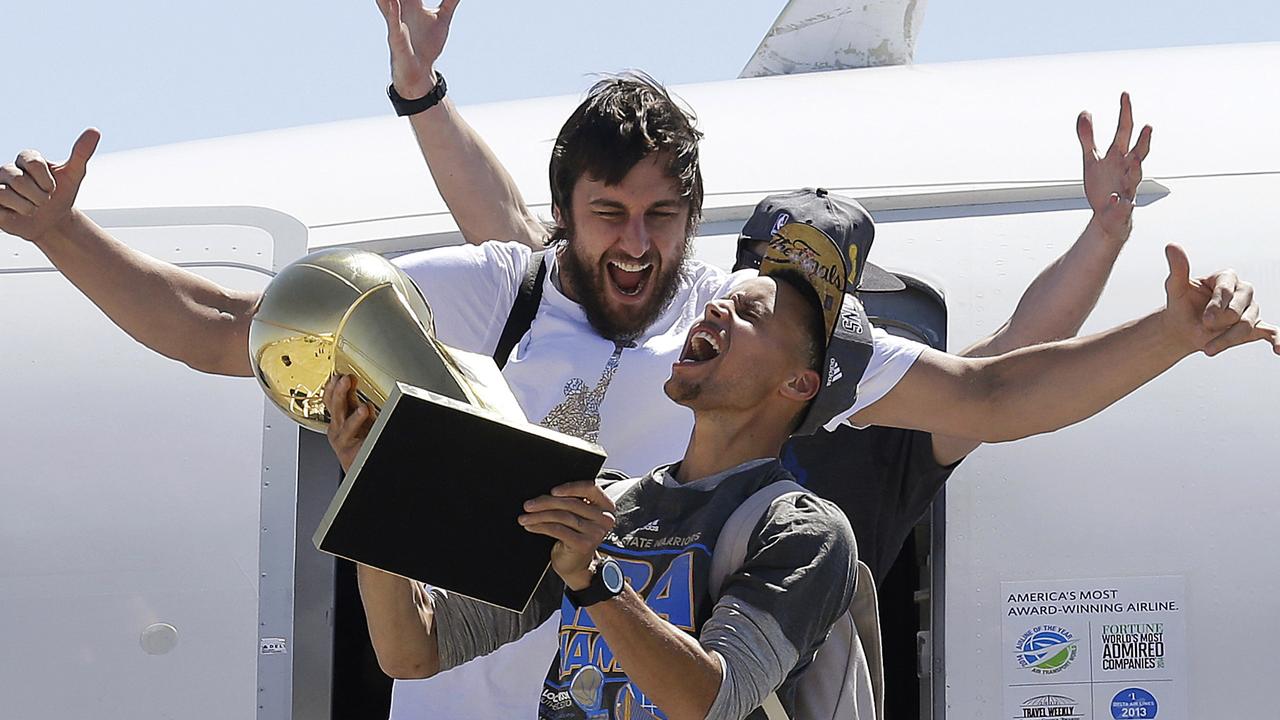 FOR USE AS DESIRED, YEAR END PHOTOS - FILE - Golden State Warriors guard Stephen Curry, foreground, yells as he carries the Larry O'Brien NBA championship trophy in front of center Andrew Bogut after the team's flight landed in Oakland, Calif., Wednesday, June 17, 2015. The Warriors defeated the Cleveland Cavaliers to win their first NBA championship since 1975. (AP Photo/Jeff Chiu, File)