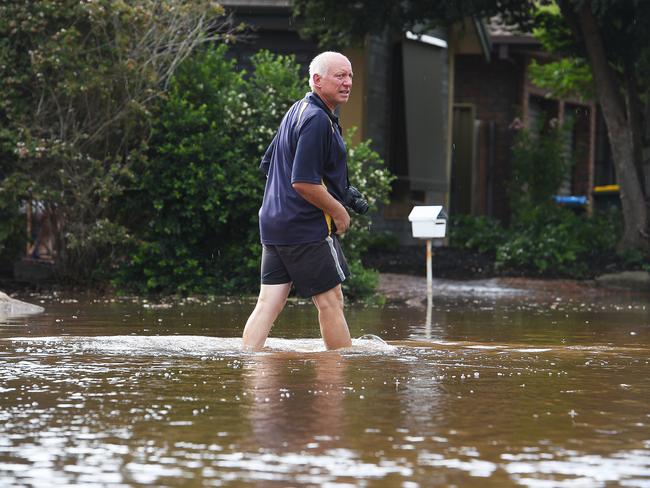 Linton Schiller wades through water near his house flooded in Willow Drive. Picture: Roger Wyman