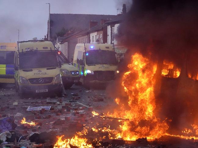 Riot police hold back protesters near a burning police vehicle in Southport, England. Picture: Getty Images