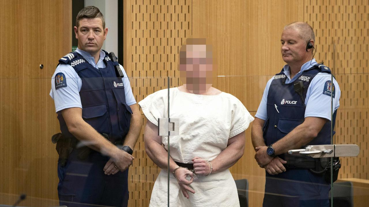 The man charged in relation to the Christchurch massacre makes a sign to the camera during his appearance in the Christchurch District Court.