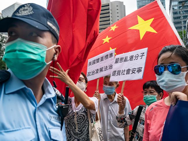 Pro-Beijing supporters hold Chinese national flags and placards as they take part in a Hong Kong rally. Picture: Anthony Kwan/Getty Images