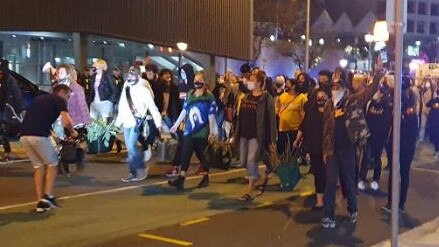 Protesters march to the police headquarters in Roma Street.