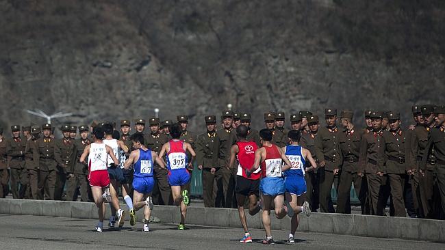 Run for your lives ... marathon runners pass by a long row of North Korean soldiers as th