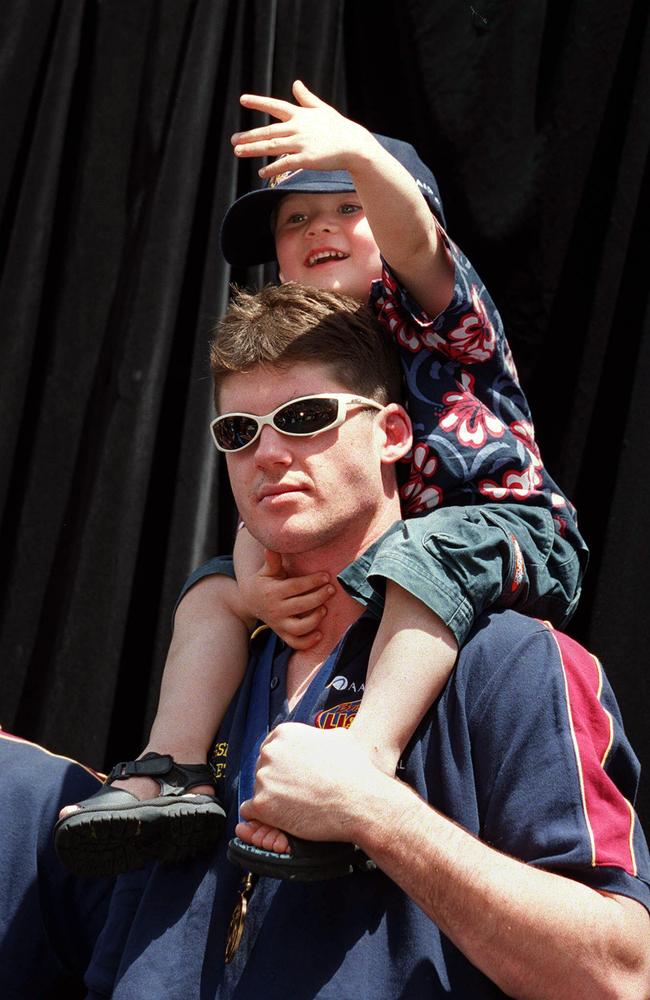 Bailey Lambert hitches a ride on the shoulders of Jonathan Brown during a Brisbane Lions premiership parade.