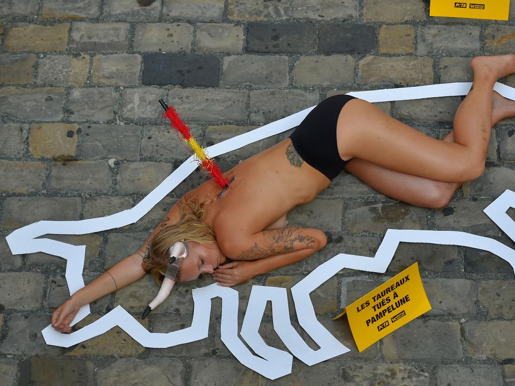 A pro-animal rights activist lies on the ground next to a placard reading "Bulls killed in Pamplona" as part of the PETA protest. Picture: AFP