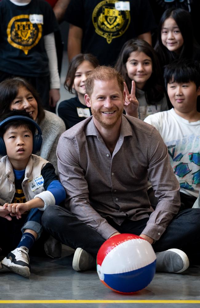 A cheeky boy makes the bunny ears/peace sign as Prince Harry poses for a group photo in Vancouver, Canada. Picture: Getty Images