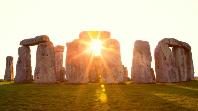 Close-up view of ancient stones during sunset at UNESCO World Heritage Site at Stonehenge, Wiltshire, UK. Sun shines through the stones. Major tourist destination, archeological and pilgrimage site during Summer Solstice and Winter Solstice. Visible grain, softer focus.