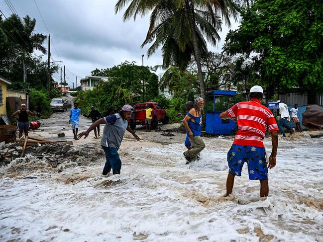 People walk through flooding from seawater in Saint James, Barbados. Picture: AFP