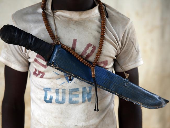 In this April 15, 2014 photo, an Anti-Balaka Christian fighter stands on the front of a looted Muslim store in Guen, some 250 kilometers north of Bangui, Central African Republic. As U.N. peacekeepers prepare to go into the Central African Republic to take over a regional mission, the death toll since fighting between Muslims and Christians started in December underscores how the aid is coming too late for thousands of victims. (AP Photo/Jerome Delay)