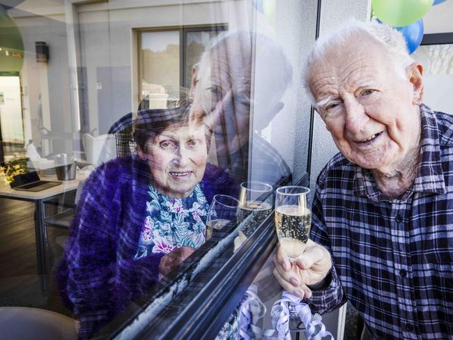 George and Shirley Fielding celebrate their 70th weddng anniversary through the glass window of her aged care facility. Picture: Nicole Cleary