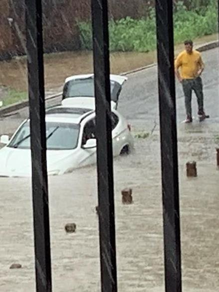 A driver looks on helplessly as a car sinks into George Khattar Lane. Picture: ParraParents/Facebook